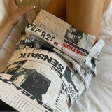 Clarissa - Off-the-shoulder playsuit with newspaper print